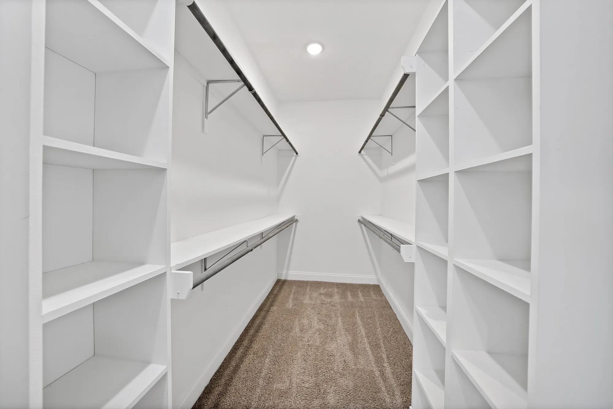 Walk-in closet featuring built-in shelving, hanging rods, and recessed lighting