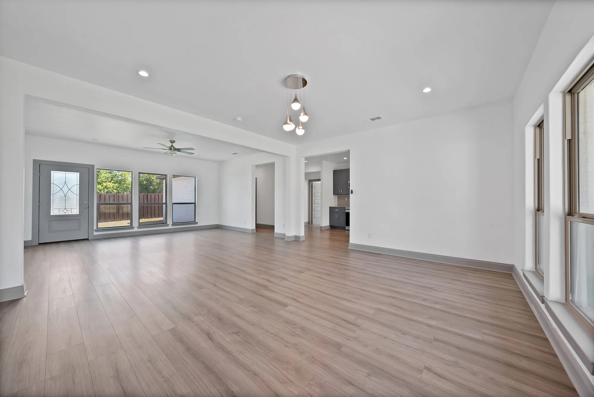 Spacious room featuring wood-finish flooring, recessed lighting, and a contemporary chandelier