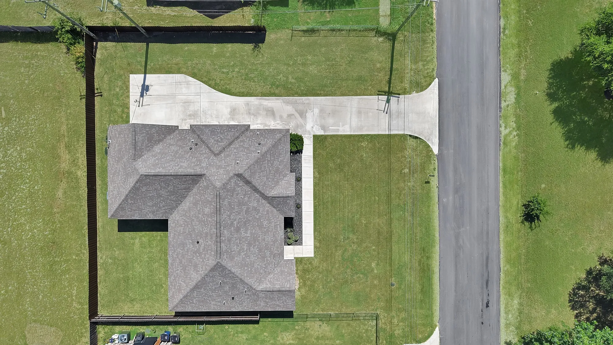 Newly constructed residence featuring a gray shingle roof and a concrete driveway