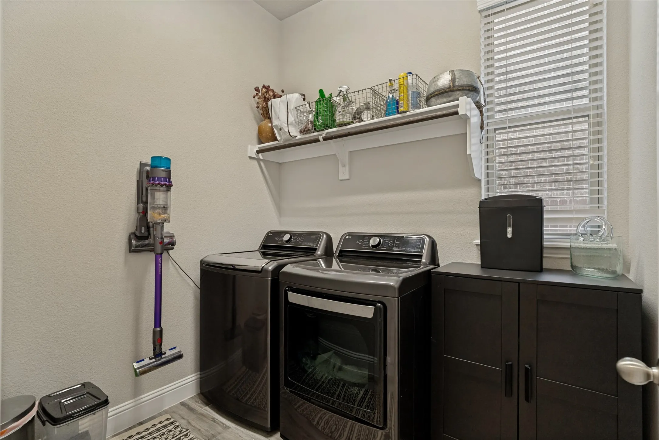 Laundry area featuring a side-by-side washer and dryer, a built-in white shelf, a window with horizontal blinds, and wood-finish flooring