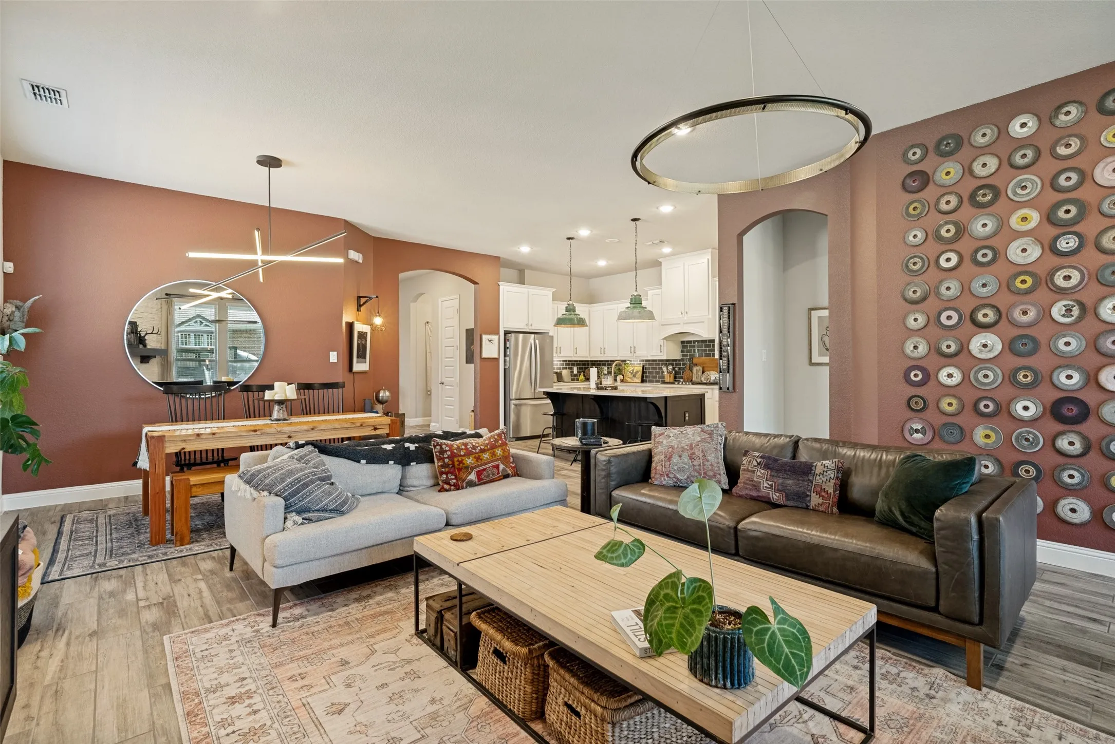 Open-concept living space featuring wood-finish flooring, a modern linear chandelier, and archway detailing