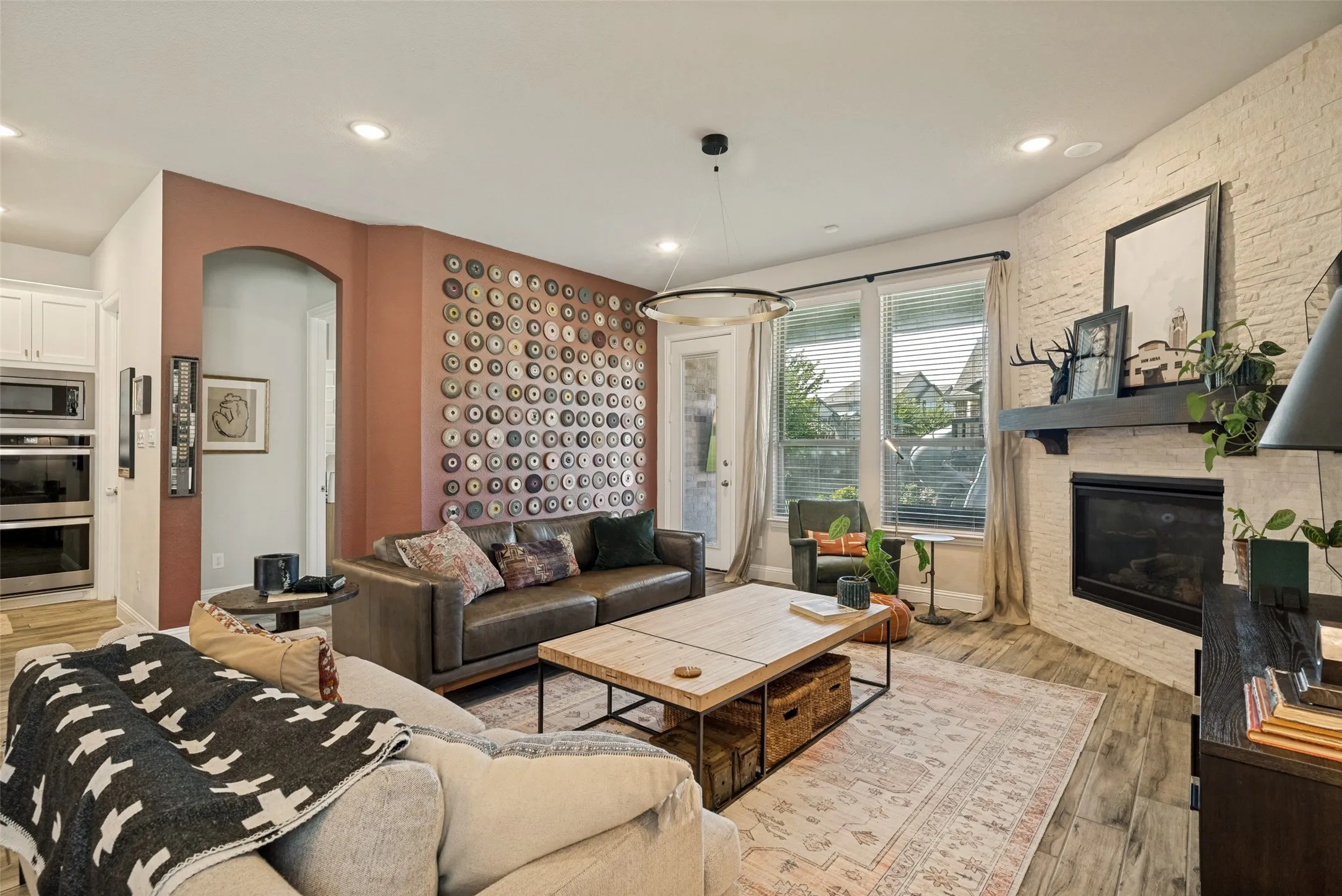 Living room featuring a corner fireplace with a dark wood mantel and a white brick surround