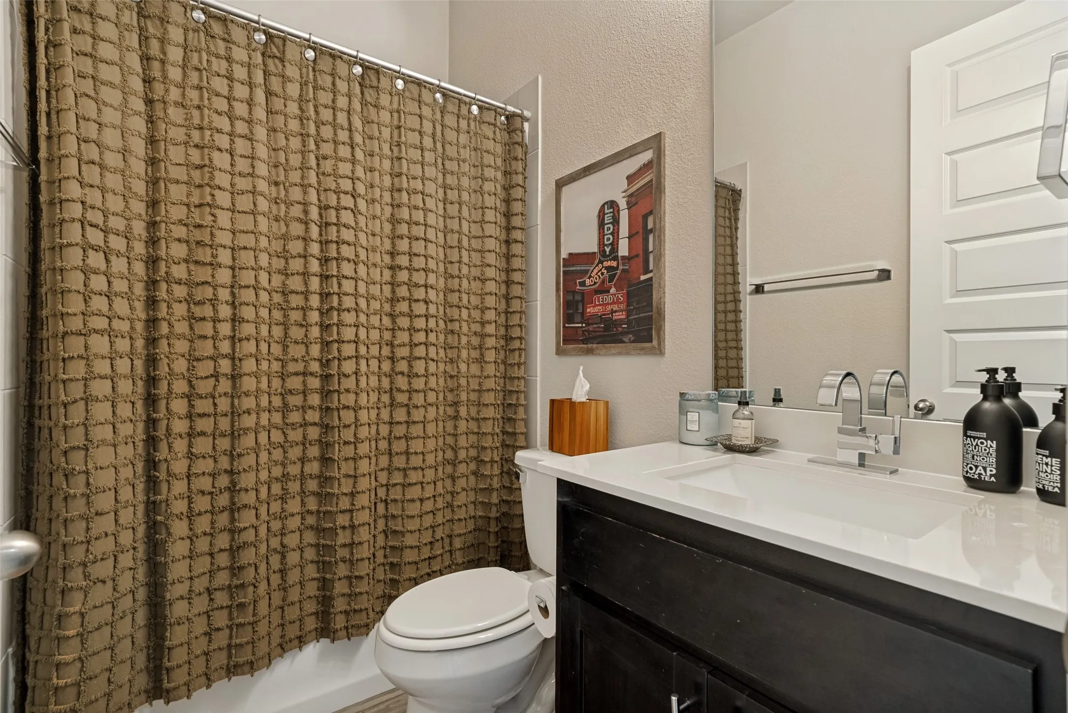 Bathroom vanity featuring a single basin sink, chrome faucet, and dark wood-finish cabinetry