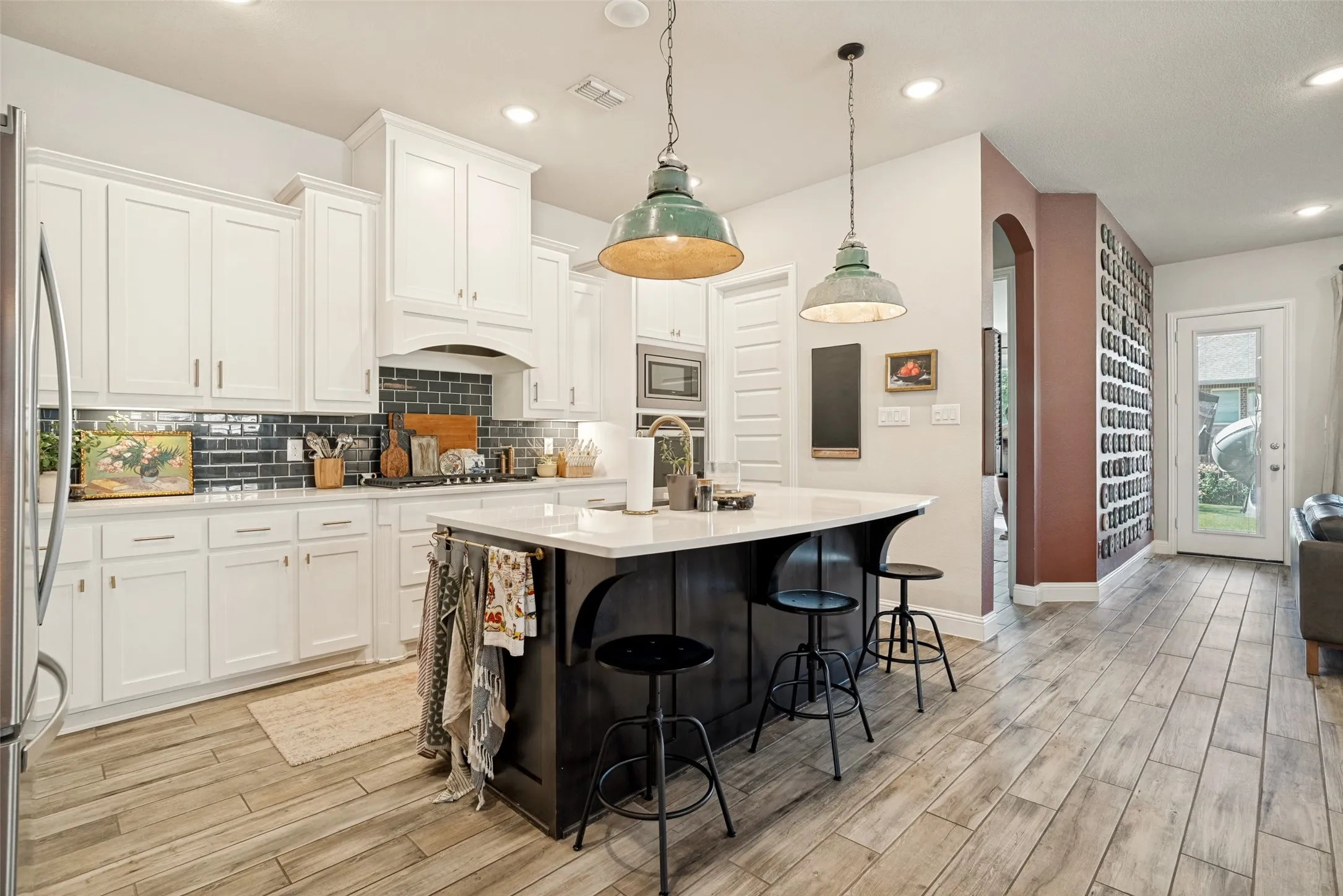 Modern kitchen featuring white cabinetry, a dark subway tile backsplash, and a central island