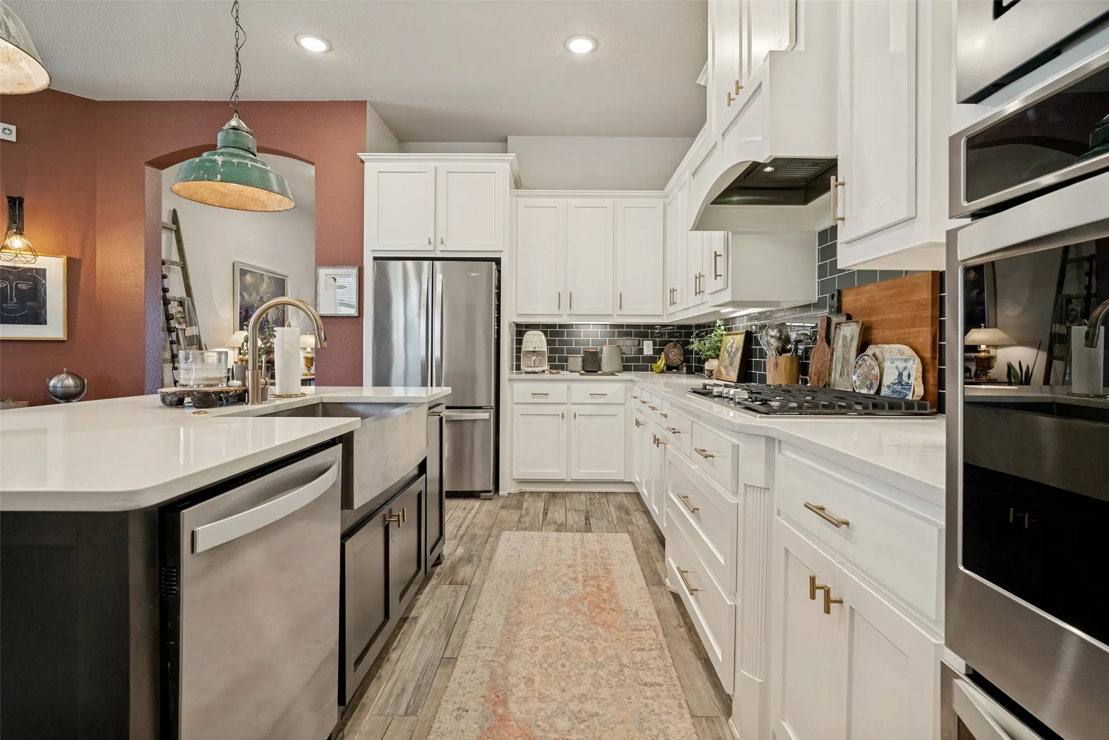 Kitchen featuring an integrated stainless steel refrigerator, built-in wall oven, gas cooktop, and a farm sink in the island with a stainless steel dishwasher