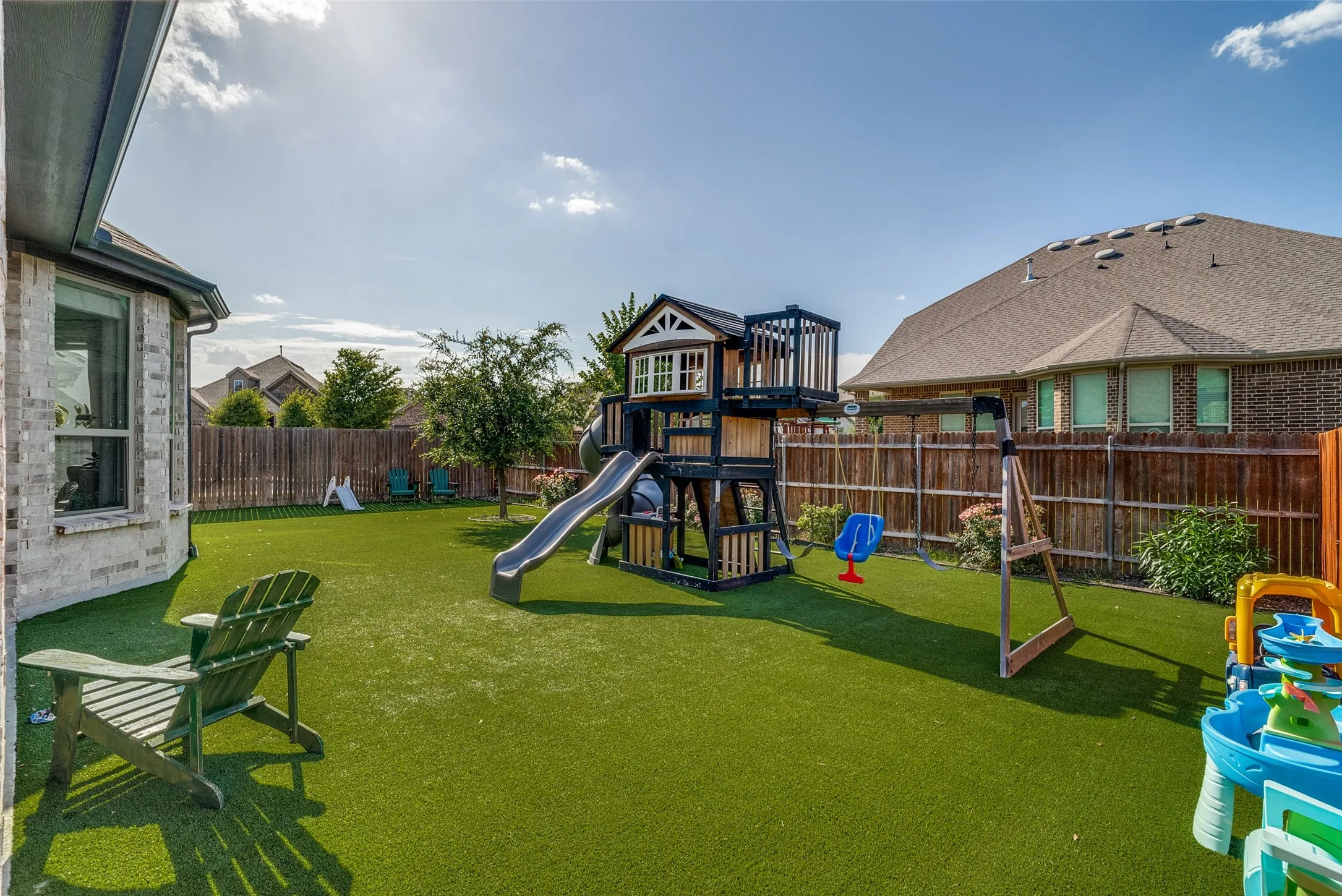 Expansive backyard featuring artificial turf, a wood privacy fence