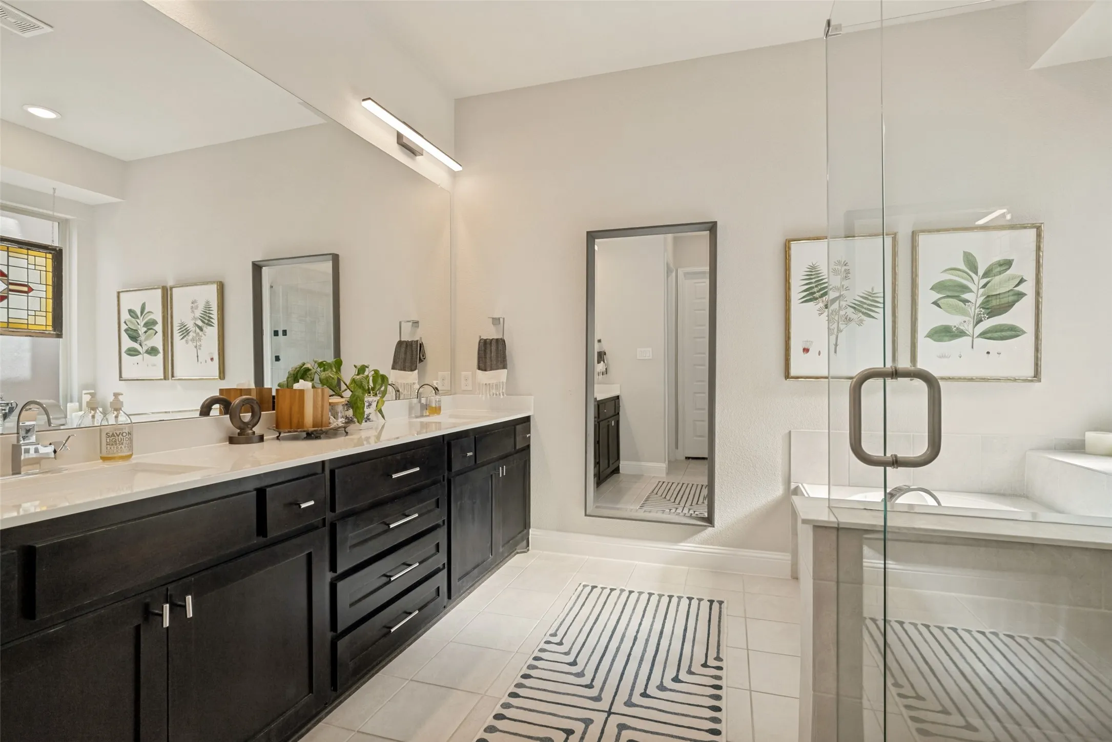 Dual vanity with dark wood cabinetry and integrated sinks, complemented by an expansive mirror