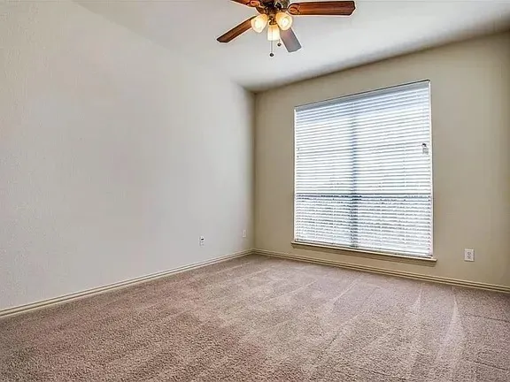 Neutral-toned wall finishes with a large window featuring blinds, complemented by a ceiling fan with integrated lighting