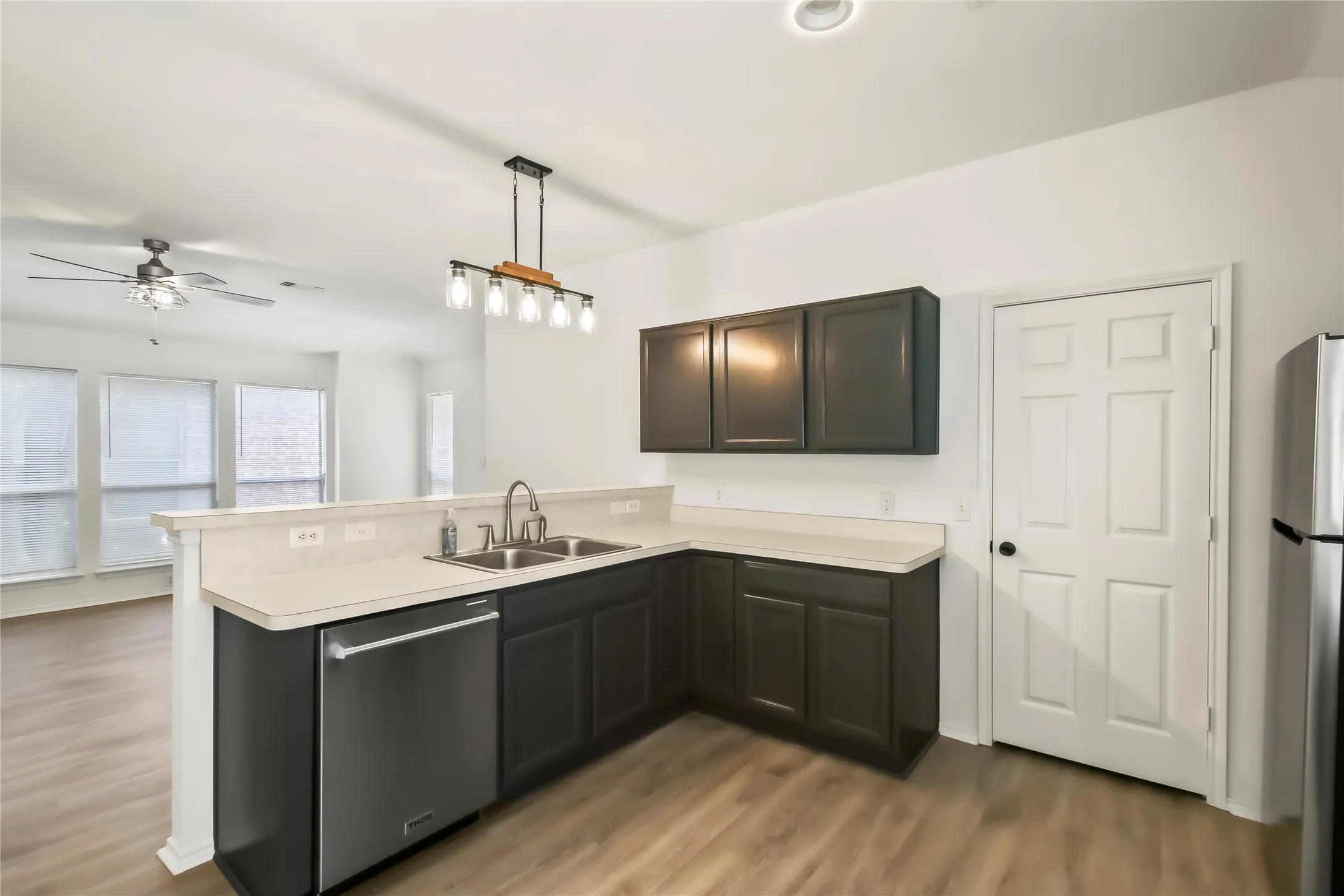 Kitchen featuring dark cabinetry, light countertops, and a dual basin sink with a gooseneck faucet