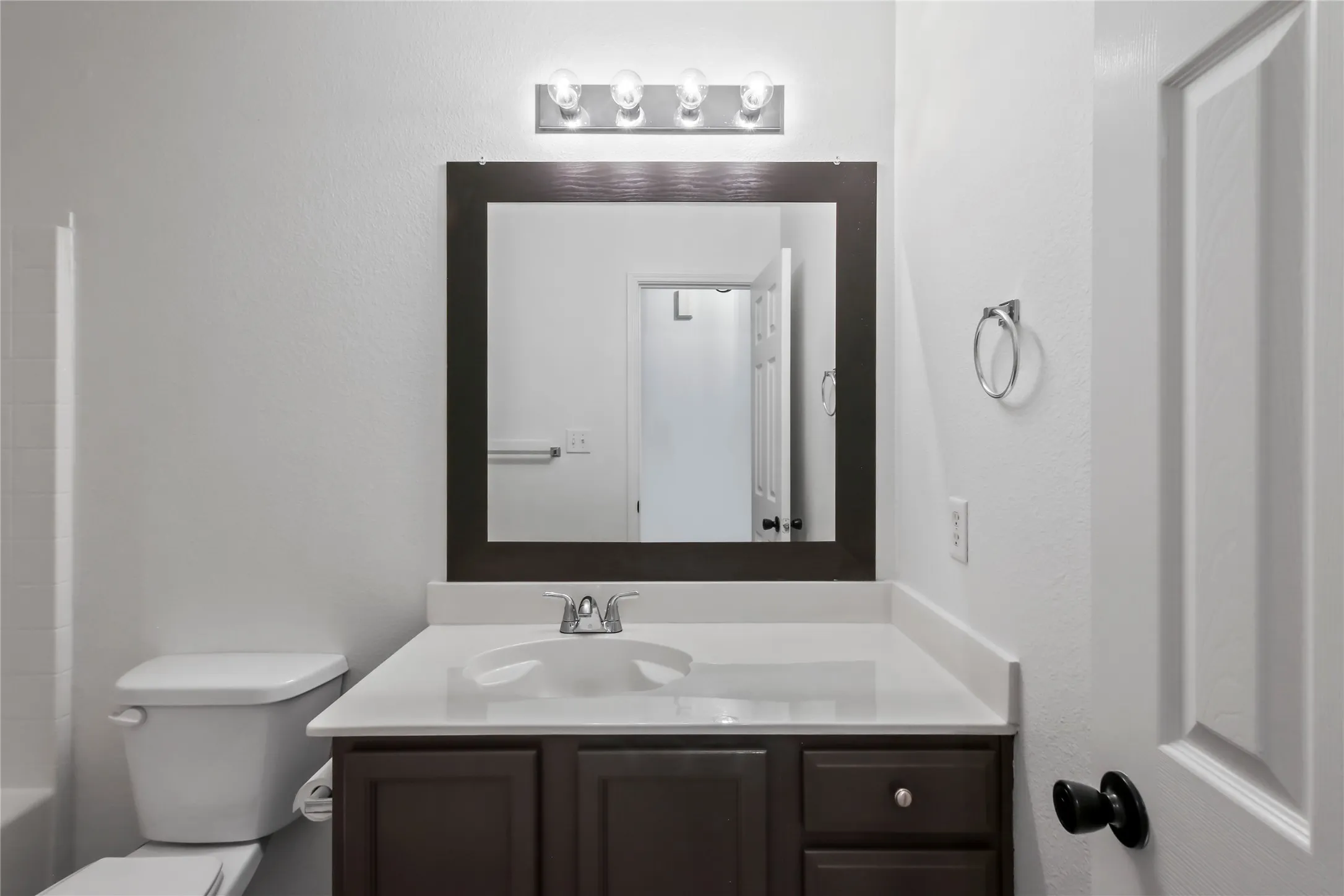 Bathroom vanity featuring a white countertop, undermount sink, and dark wood-finish cabinetry