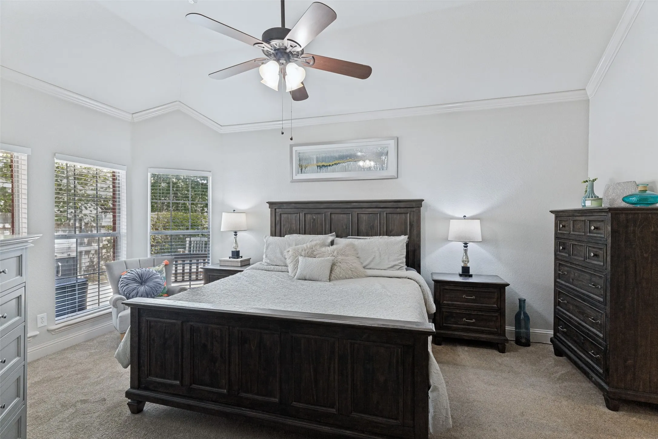 Bedroom with plush carpet flooring, tray ceiling, sitting area, and crown molding