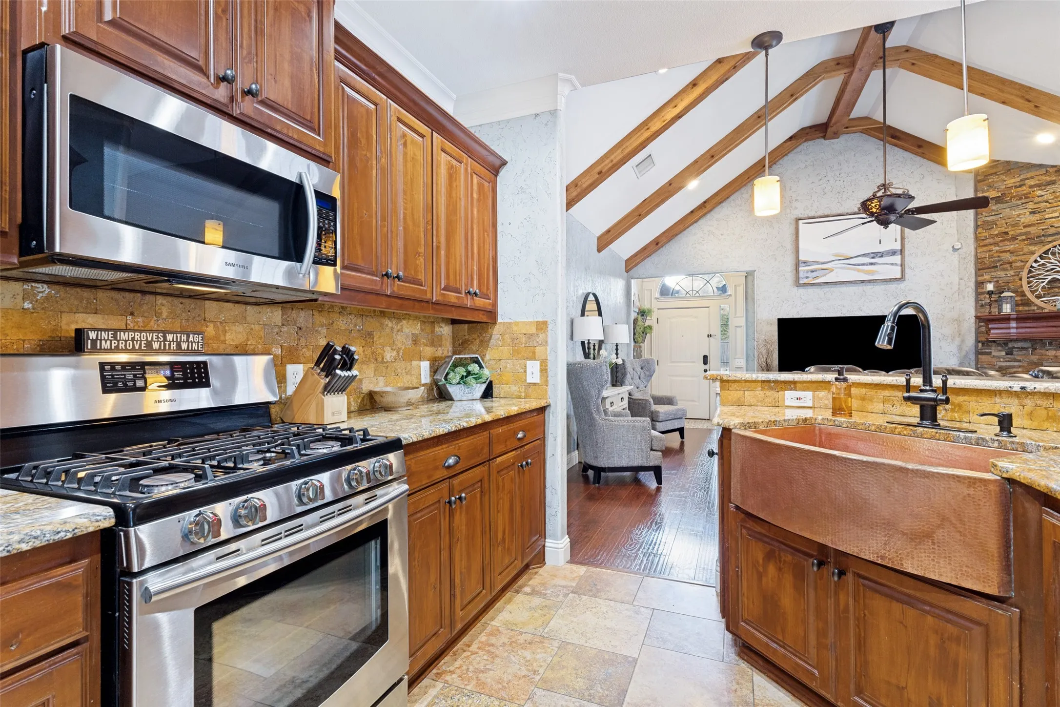 Kitchen showcasing a copper farmhouse sink with a black gooseneck faucet, granite countertops, and wood cabinetry
