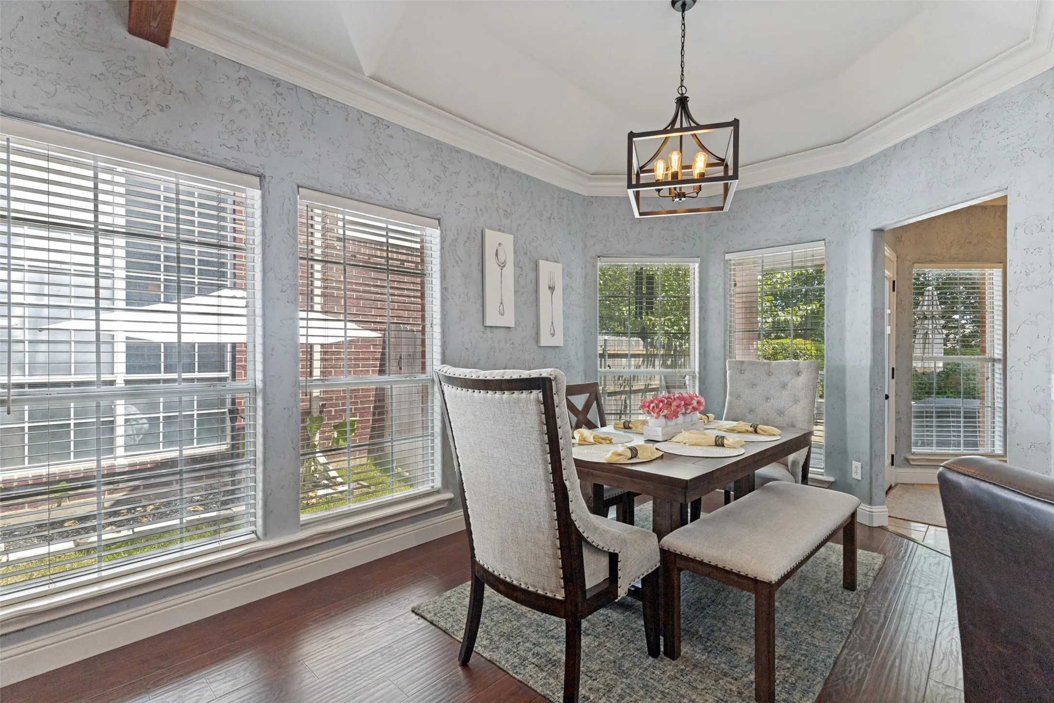 Bay window dining area featuring wood-finish flooring, textured walls, and a multi-pane window configuration