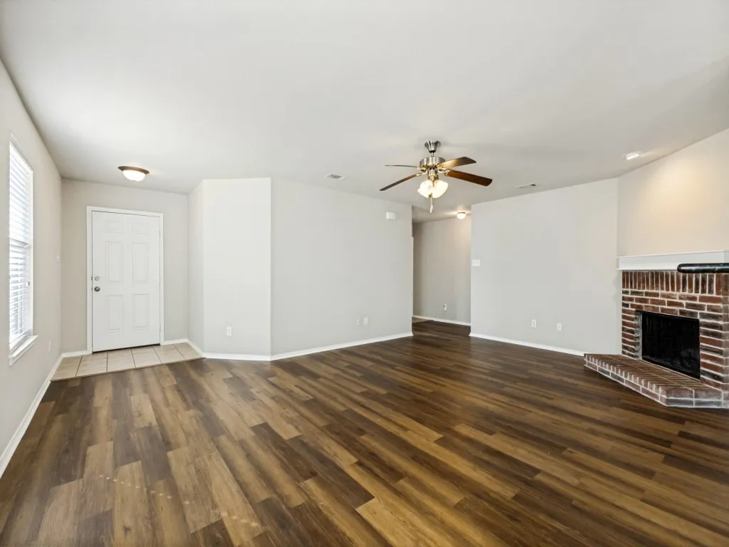 Spacious living area featuring wood-finish flooring, a brick fireplace with a mantel, a ceiling fan, and recessed lighting
