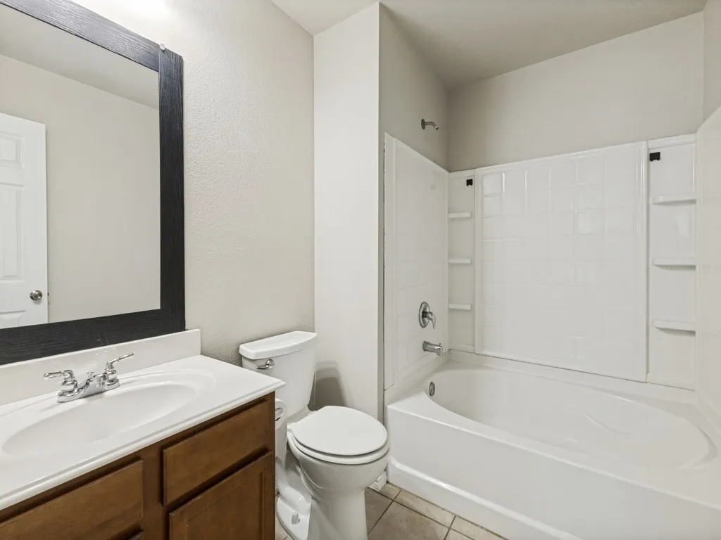 Vanity with a white countertop and integrated sink, chrome faucet, and wood-finish cabinetry