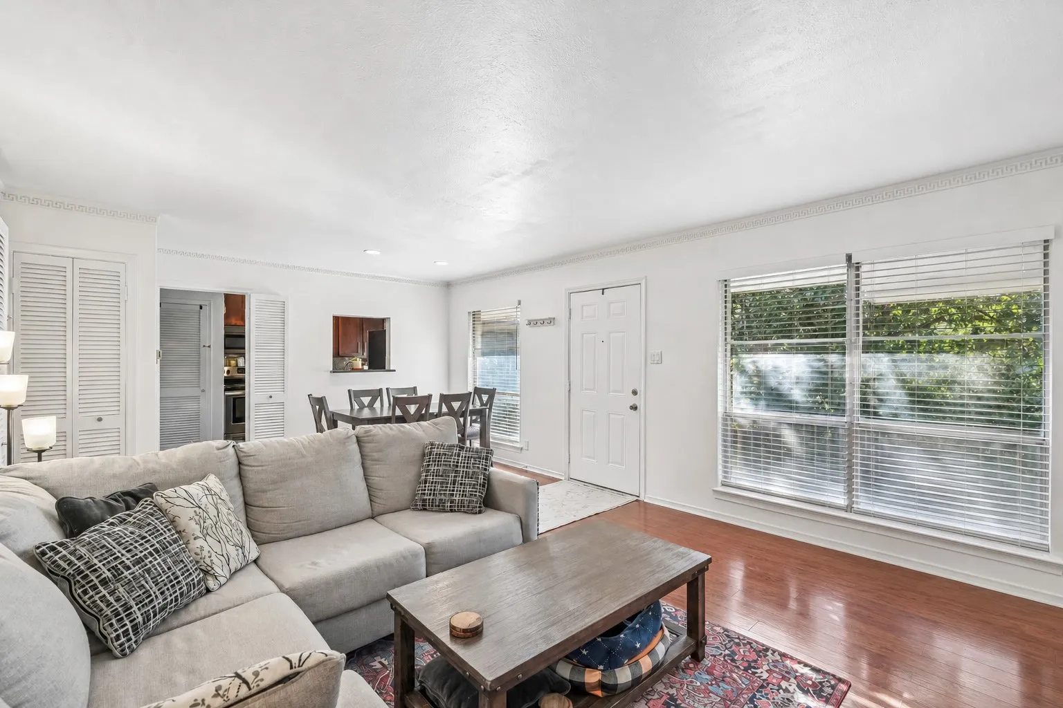Open-concept living space featuring wood-finish flooring, white walls, and decorative crown molding