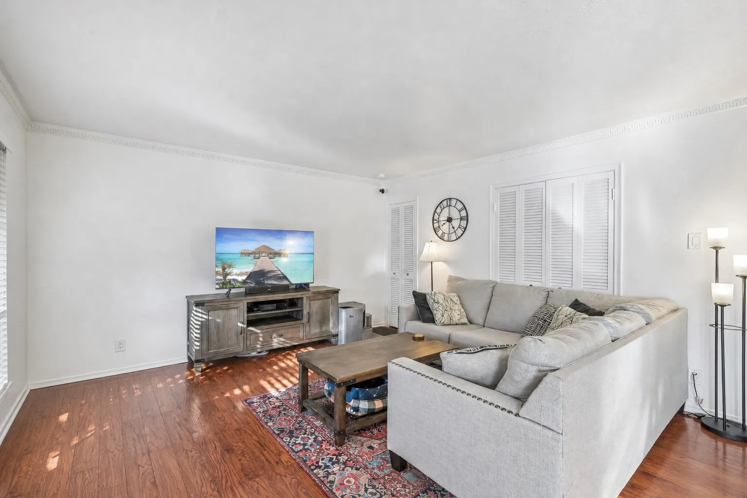 Living area featuring wood-finish flooring, white crown molding, and white walls