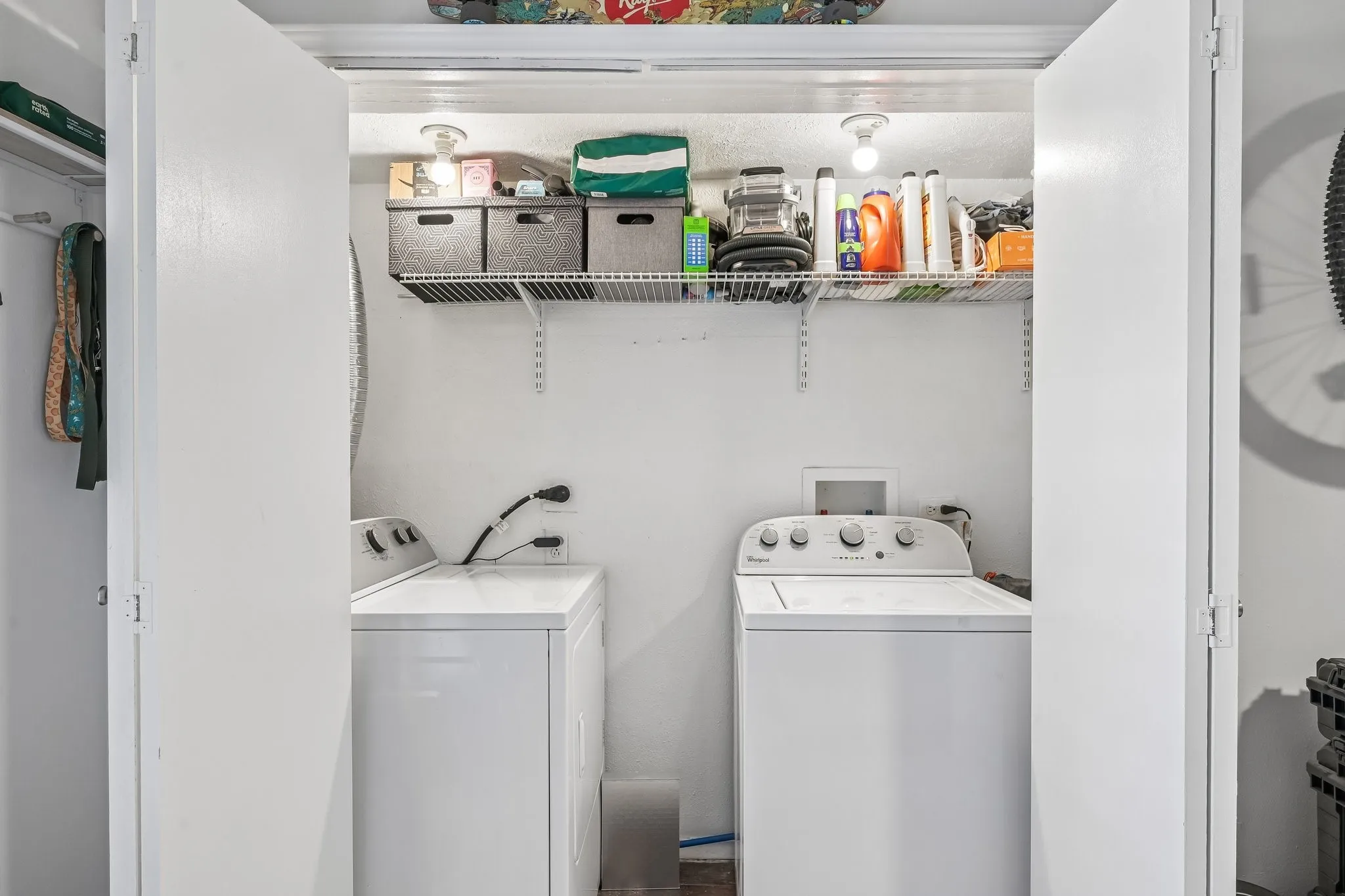 Dedicated laundry closet featuring a top-load washing machine, a front-load dryer, and overhead wire shelving