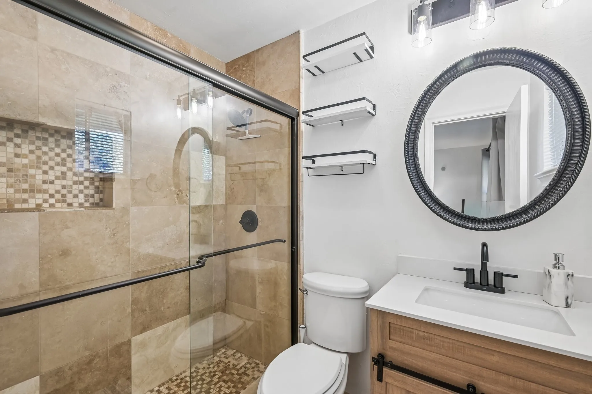 Shower with sliding glass enclosure, stone tile walls, and a recessed tile niche
