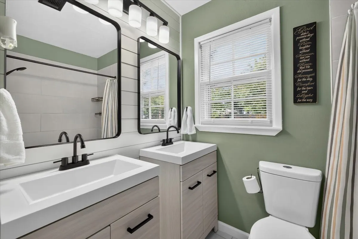 Renovated hall bathroom with dual vanities and tiled tub/shower