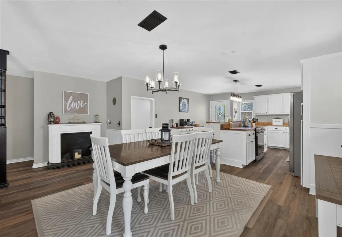 Dining area with decorative fireplace and view into updated kitchen
