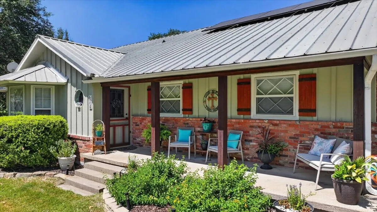 Covered front porch with brick accents, metal roof, and updated exterior paint