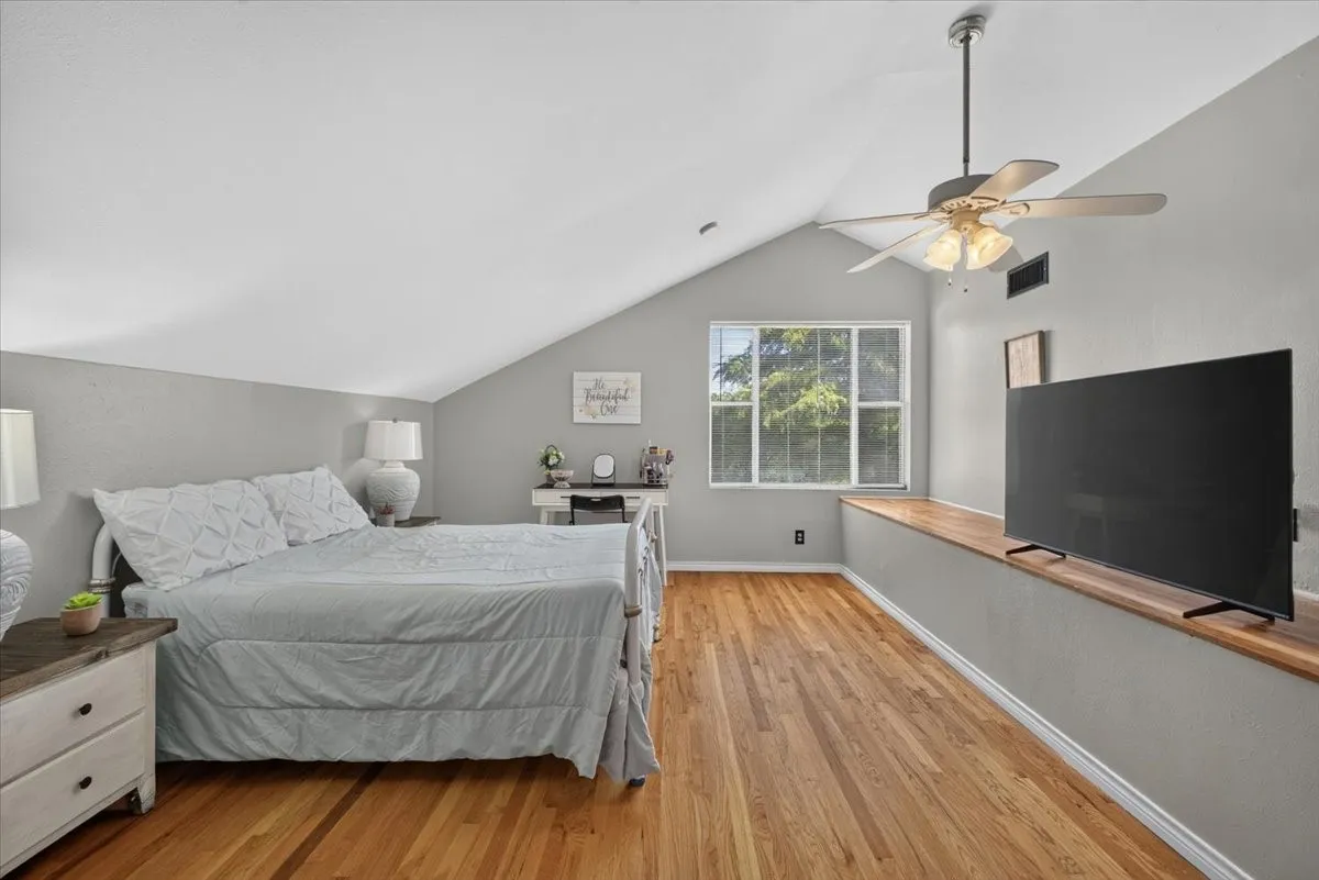 Upstairs bedroom with hardwood flooring, natural light, and built-in ledge