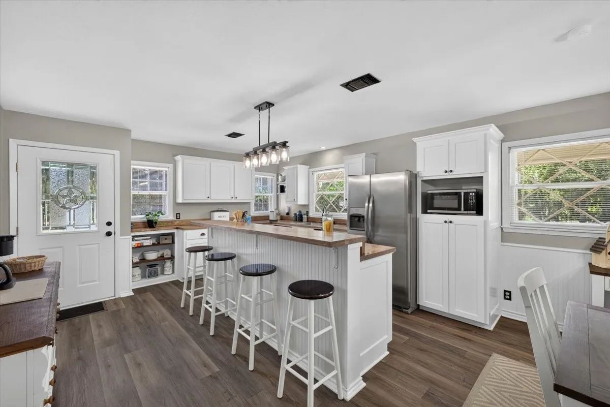 Refreshed kitchen with butcher block countertops, island seating, and stainless appliances
