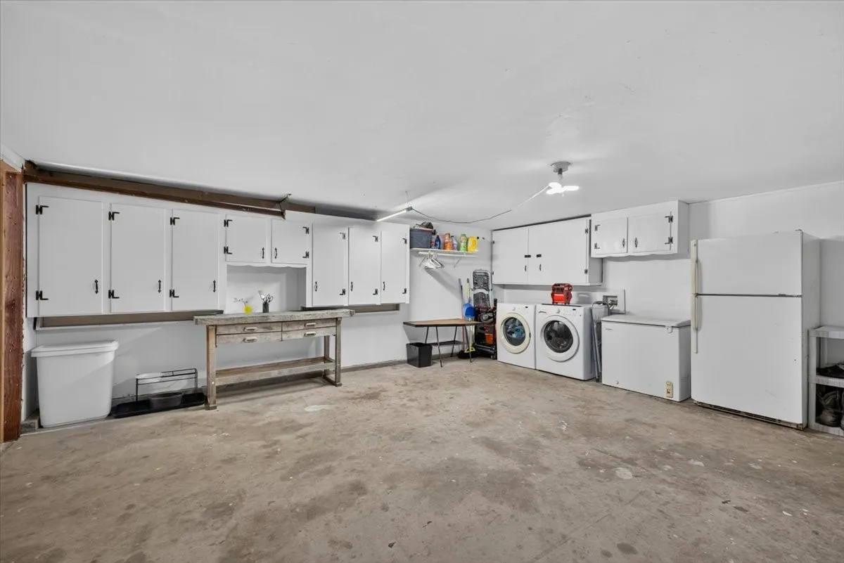 Garage area currently used for laundry, storage, and workshop space