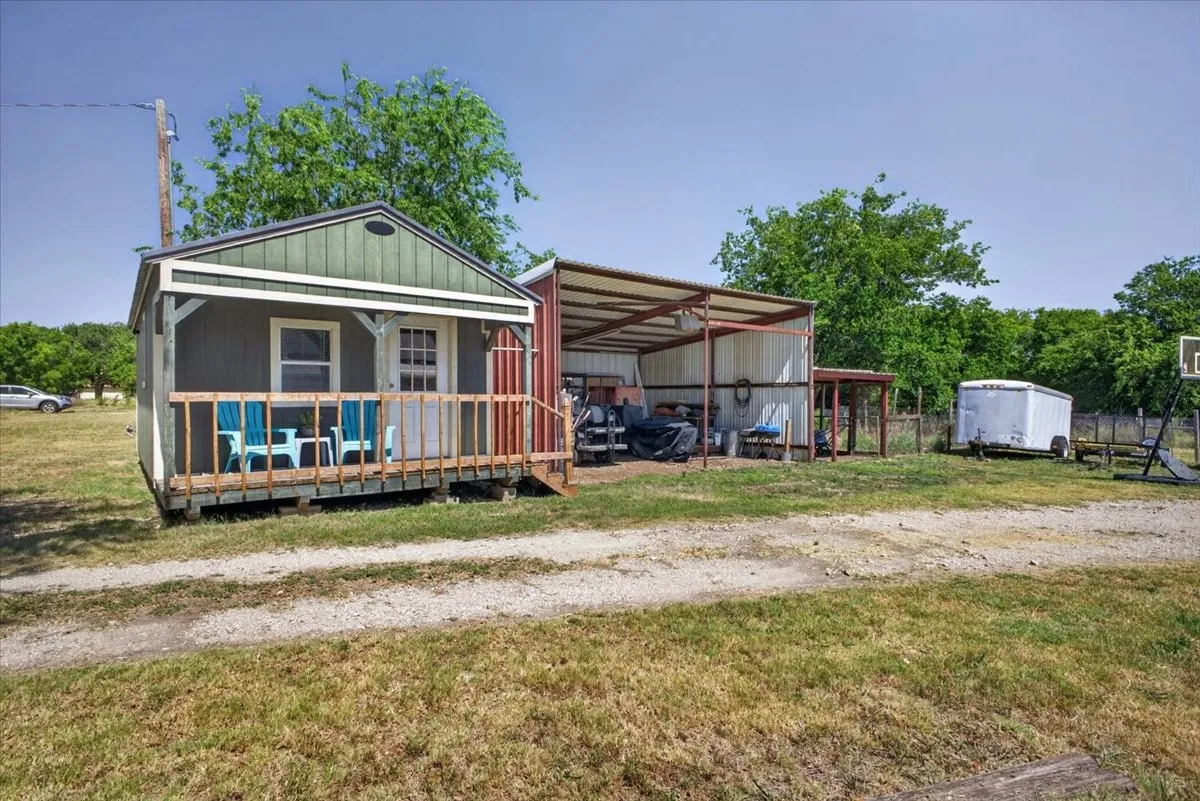 Detached studio/workshop with electricity, window unit, porch, and nearby covered equipment space
