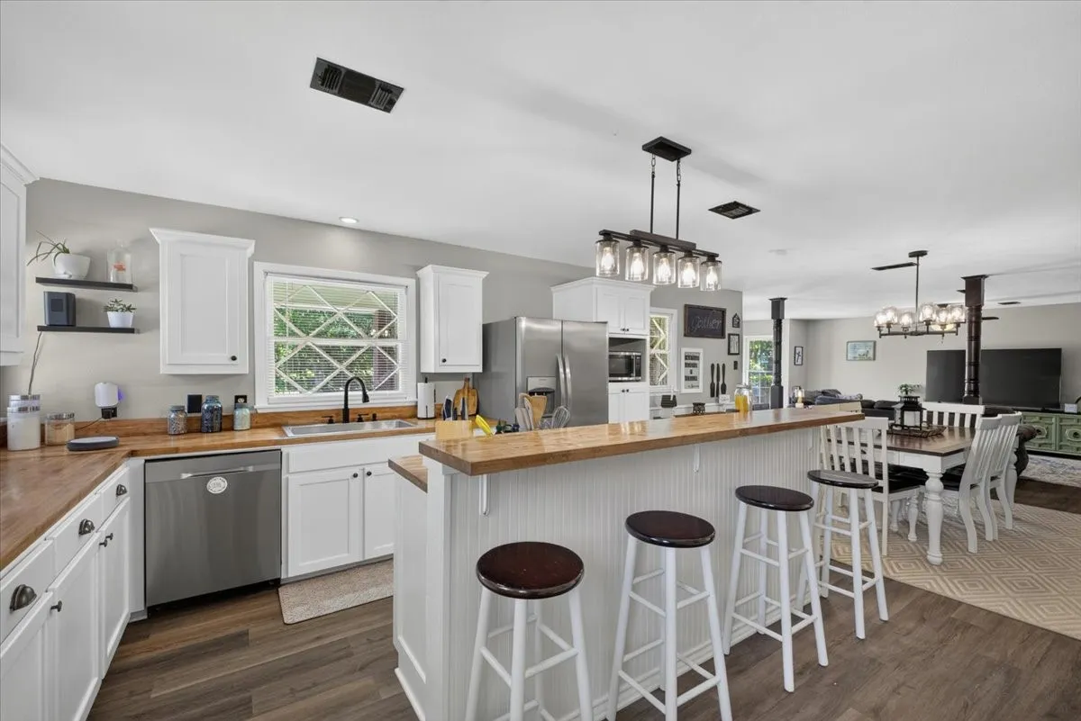 Kitchen features farmhouse sink, butcher block countertops, and open dining access