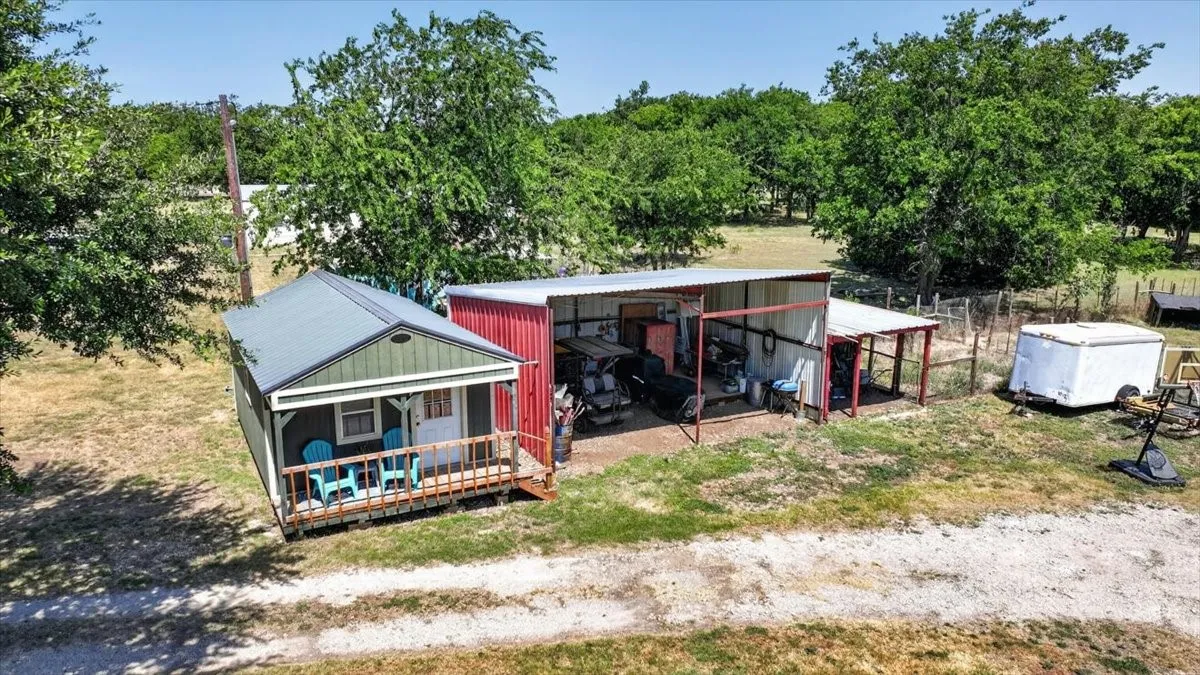 Aerial view of detached studio/workshop, covered equipment space, and gravel drive
