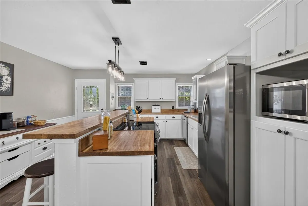 Kitchen with butcher block countertops, painted cabinets, and stainless appliances