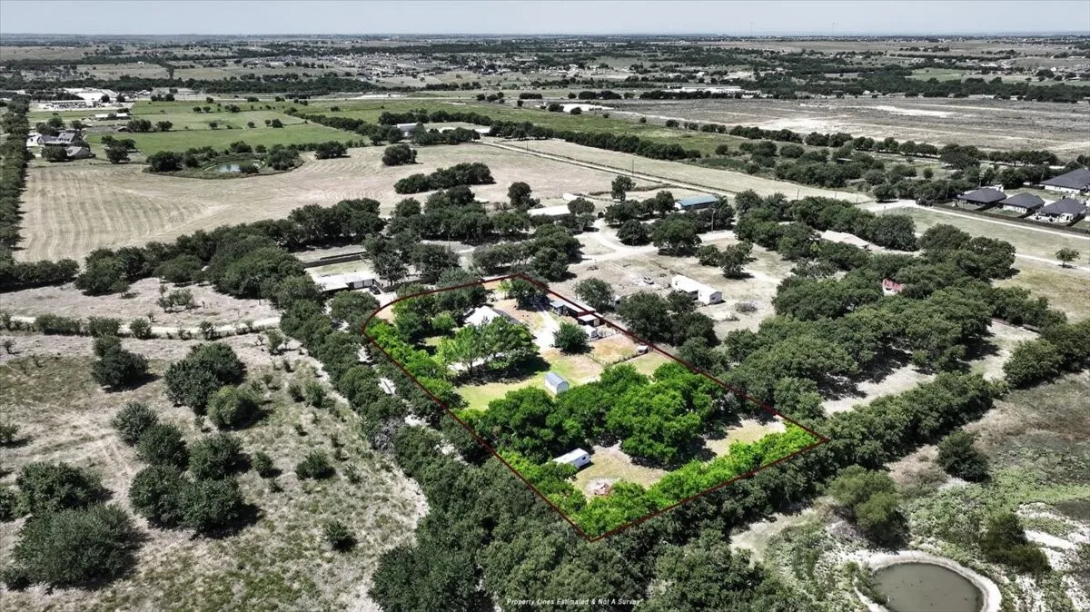 Aerial view with estimated property lines showing mature trees, and surrounding country setting