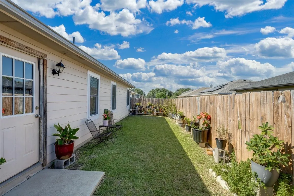 Grassed side yard featuring a privacy fence, concrete patio, and exterior siding