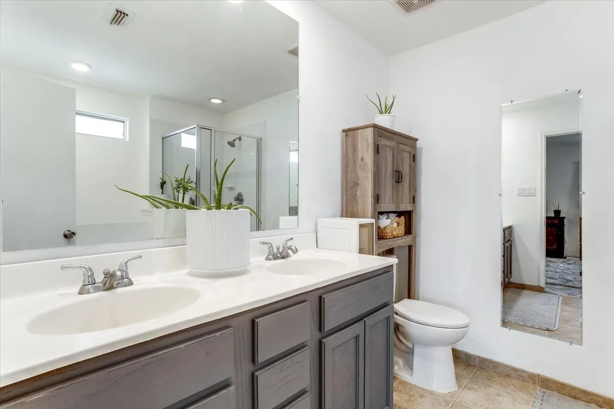 Bathroom featuring a dual vanity with white countertops, gray cabinetry, and chrome fixtures