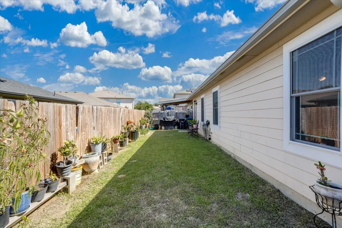 Expansive side yard featuring a manicured lawn, a wooden privacy fence, and light-colored siding