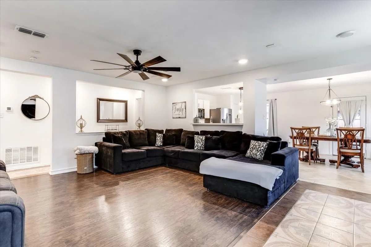 Open-concept living space featuring wood-finish flooring, a contemporary ceiling fan, recessed lighting, and a defined dining area with a chandelier