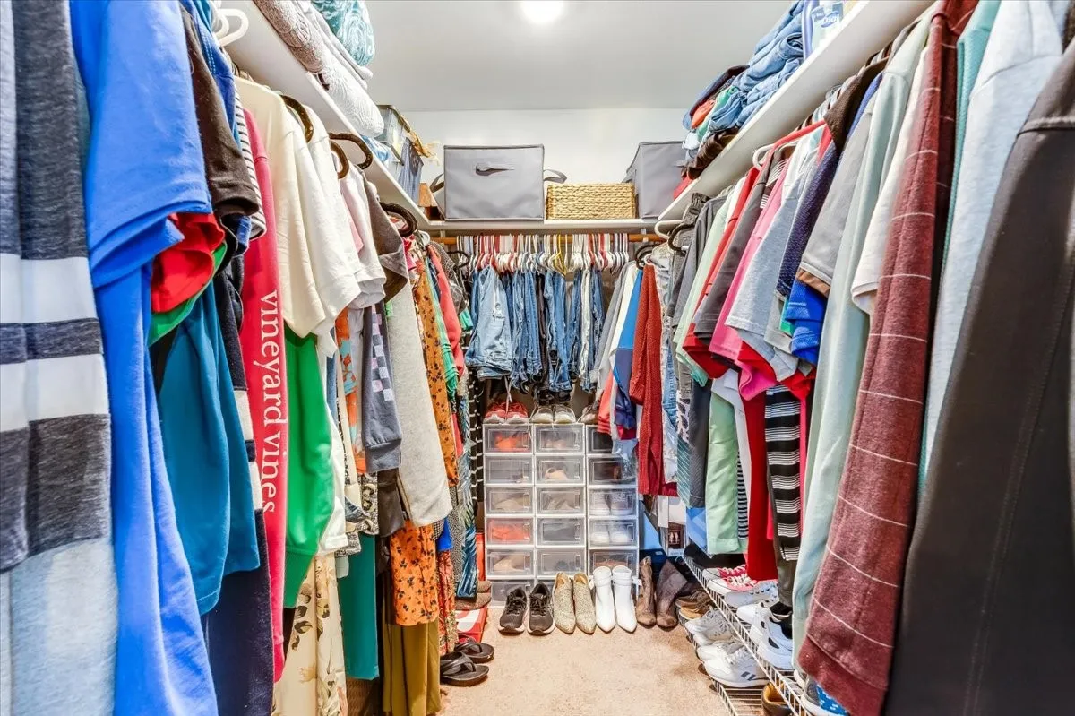 Walk-in closet featuring extensive built-in shelving and hanging rods