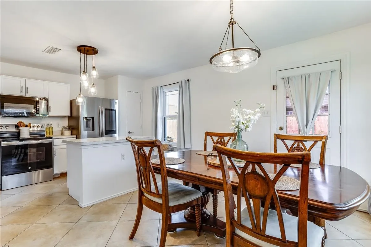 Open-concept dining area featuring tile flooring, a contemporary chandelier, and a breakfast bar