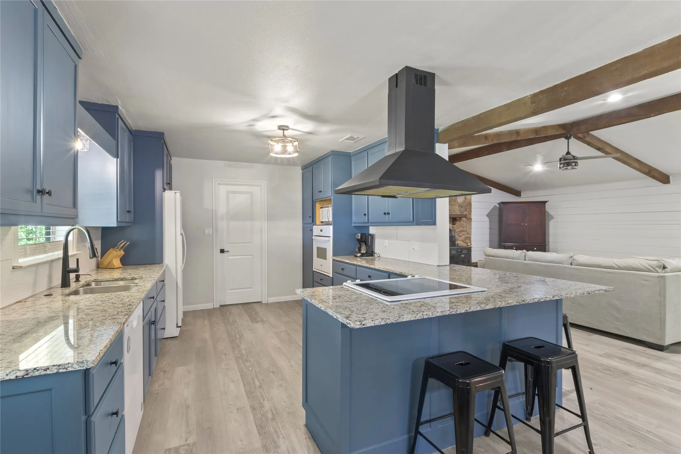 Open-concept kitchen with blue cabinetry and granite countertops