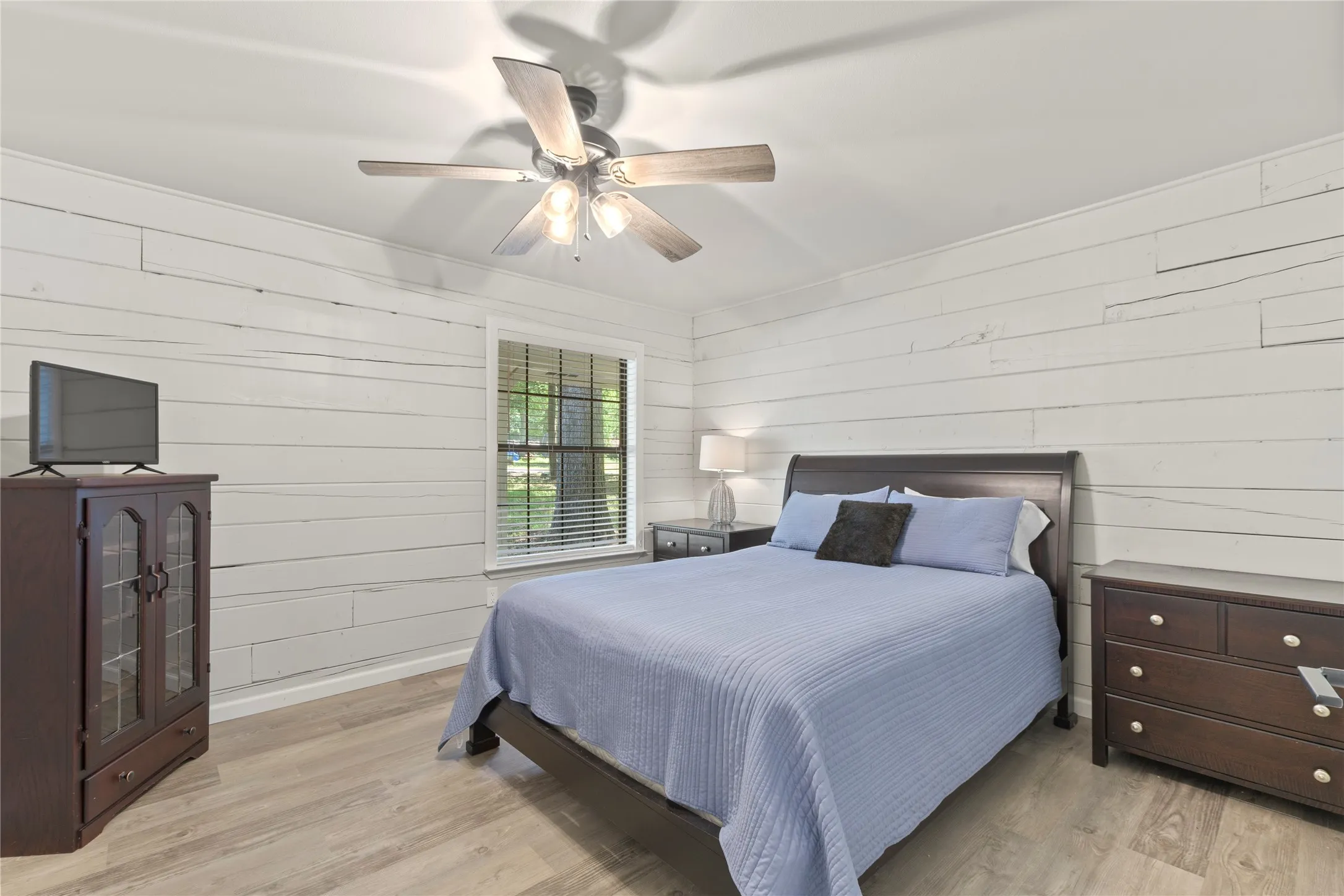 Interior room featuring white horizontal plank walls and wood-finish flooring