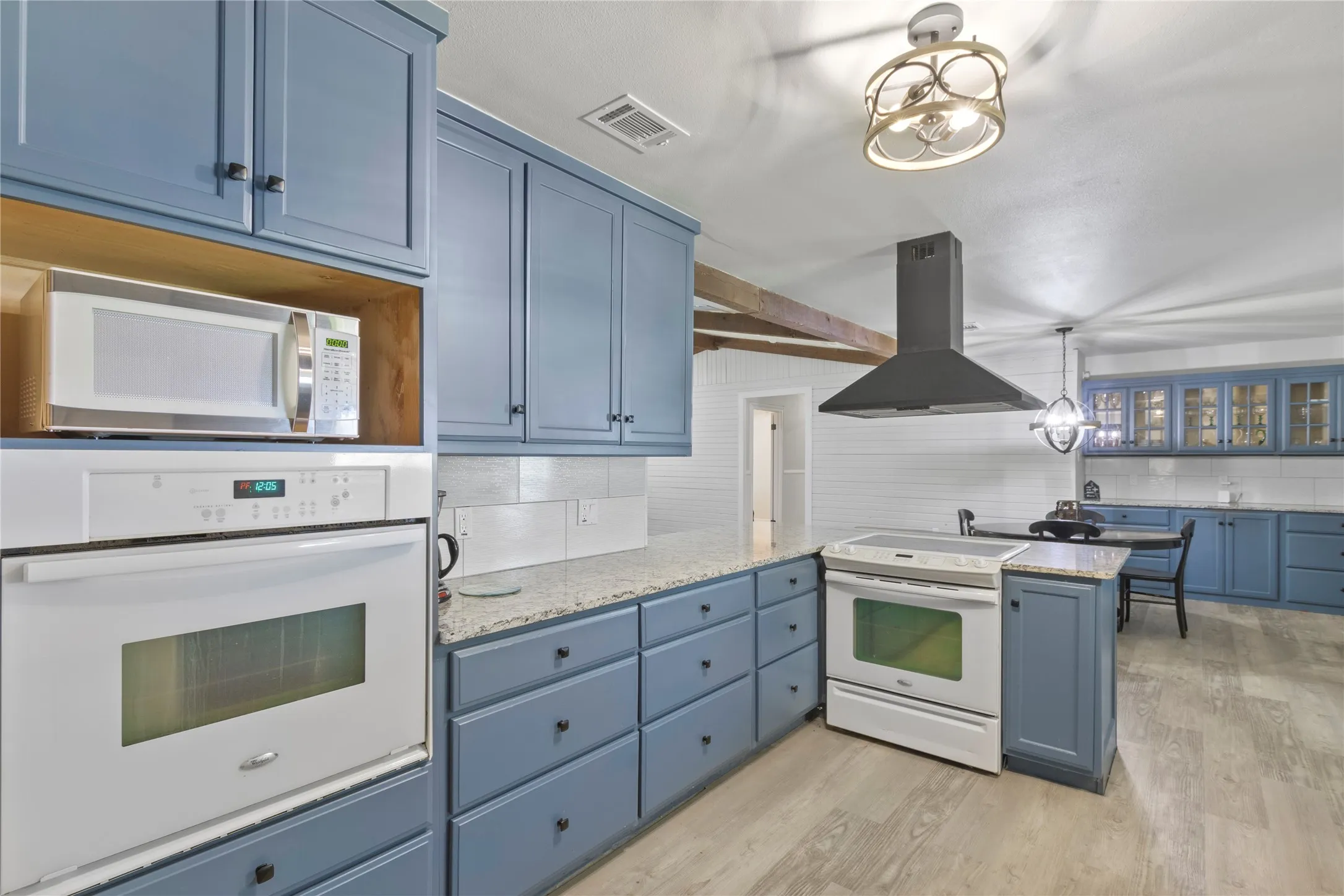 Kitchen with blue cabinetry, light-colored countertops, and wood-finish flooring