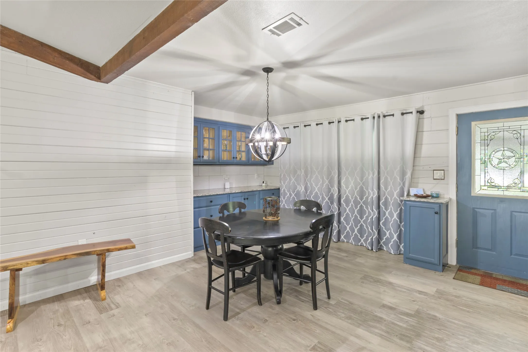 Dining area featuring light wood-finish flooring, white shiplap walls, and exposed ceiling beams