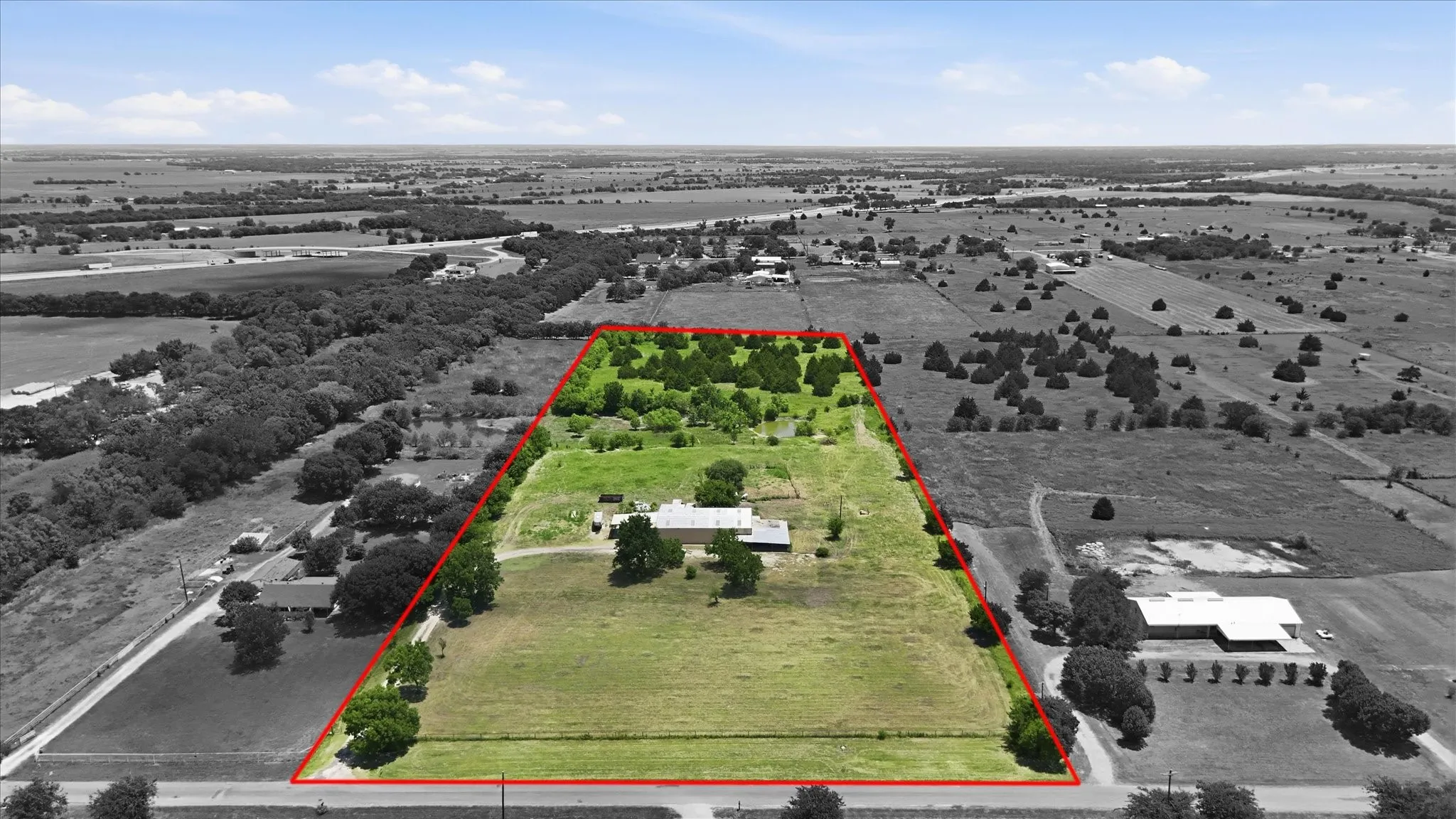Expansive property featuring a mix of open fields and mature tree coverage
