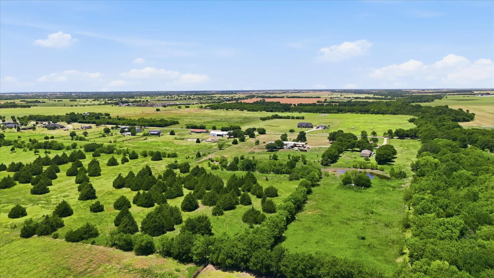 Expansive acreage featuring abundant mature trees, open green spaces, and a visible pond