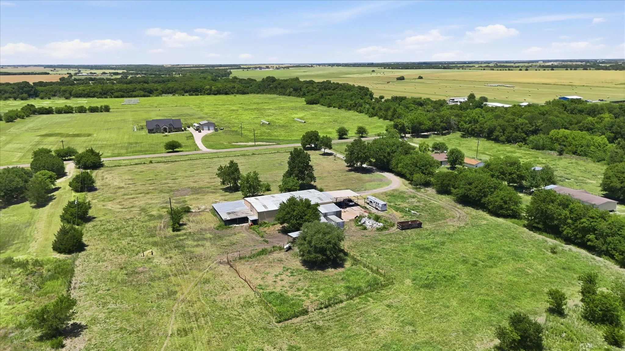 Expansive rural property featuring a main residence, multiple outbuildings, and a gravel driveway