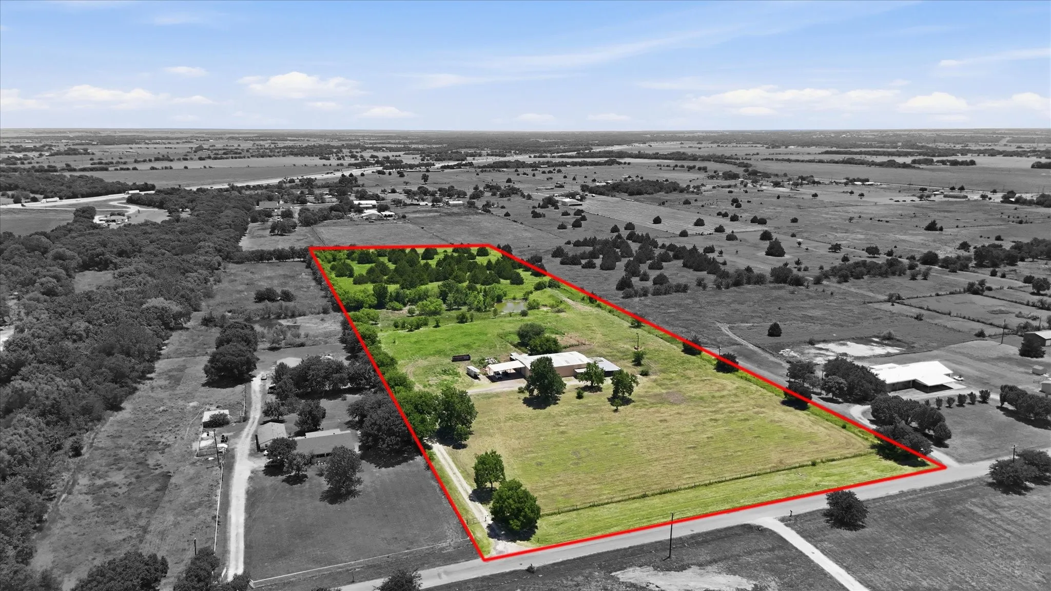 Expansive parcel featuring a defined red boundary and a mixture of open grassy areas and mature tree clusters