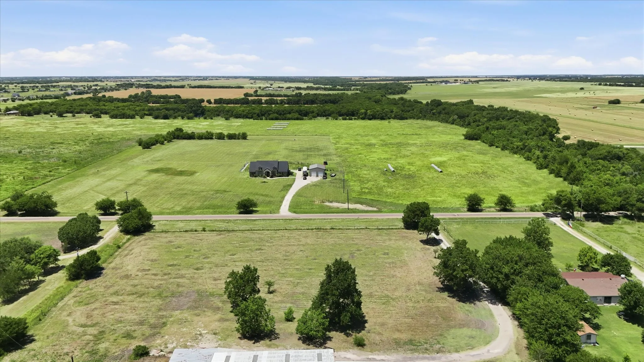 Expansive rural property featuring a main residence, a detached garage, and a long gravel driveway