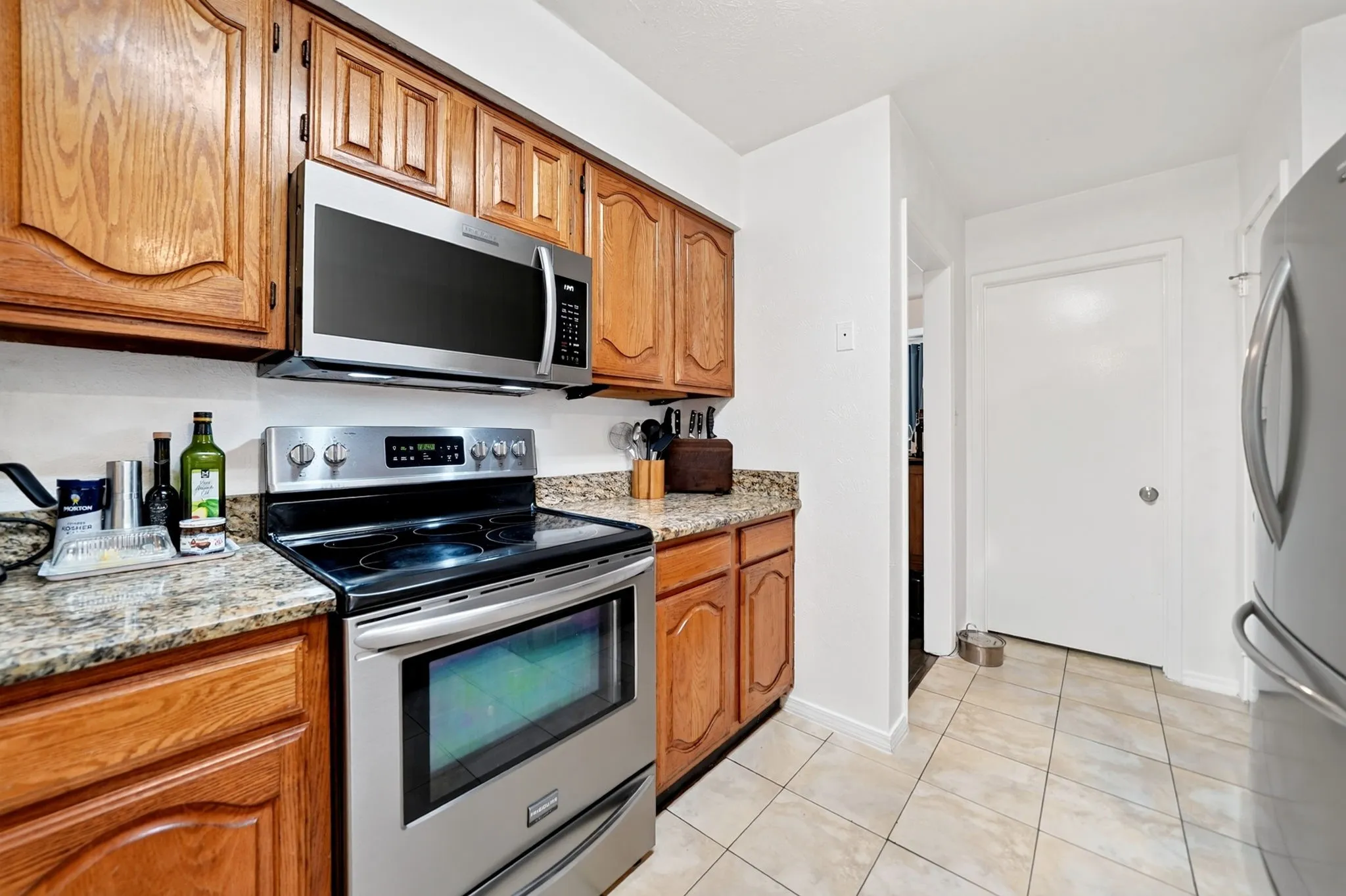 Kitchen equipped with a built-in microwave and a smooth-top electric range.